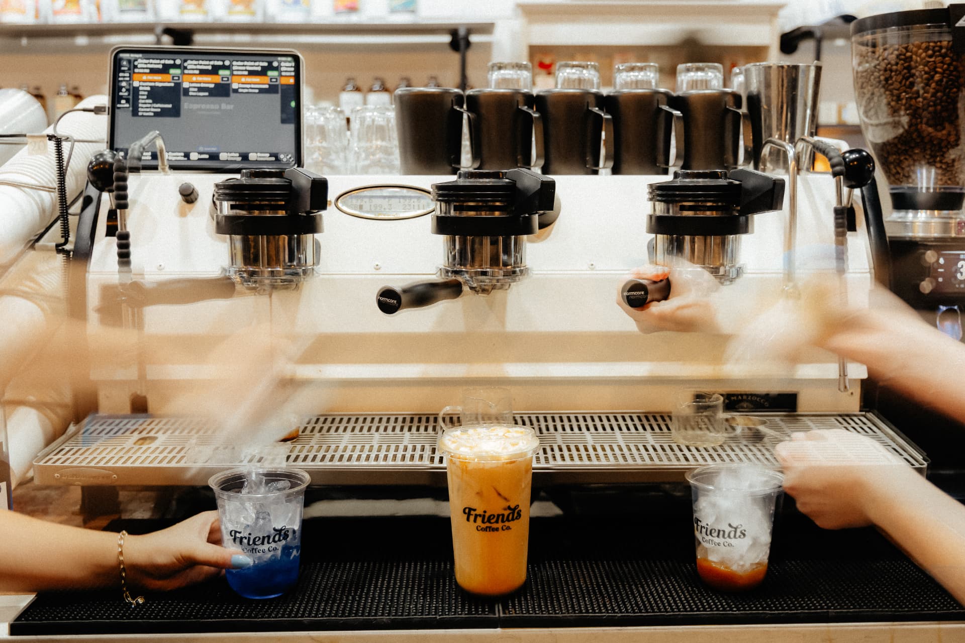 Baristas building three drinks on the espresso bar at Friends Coffee Co.