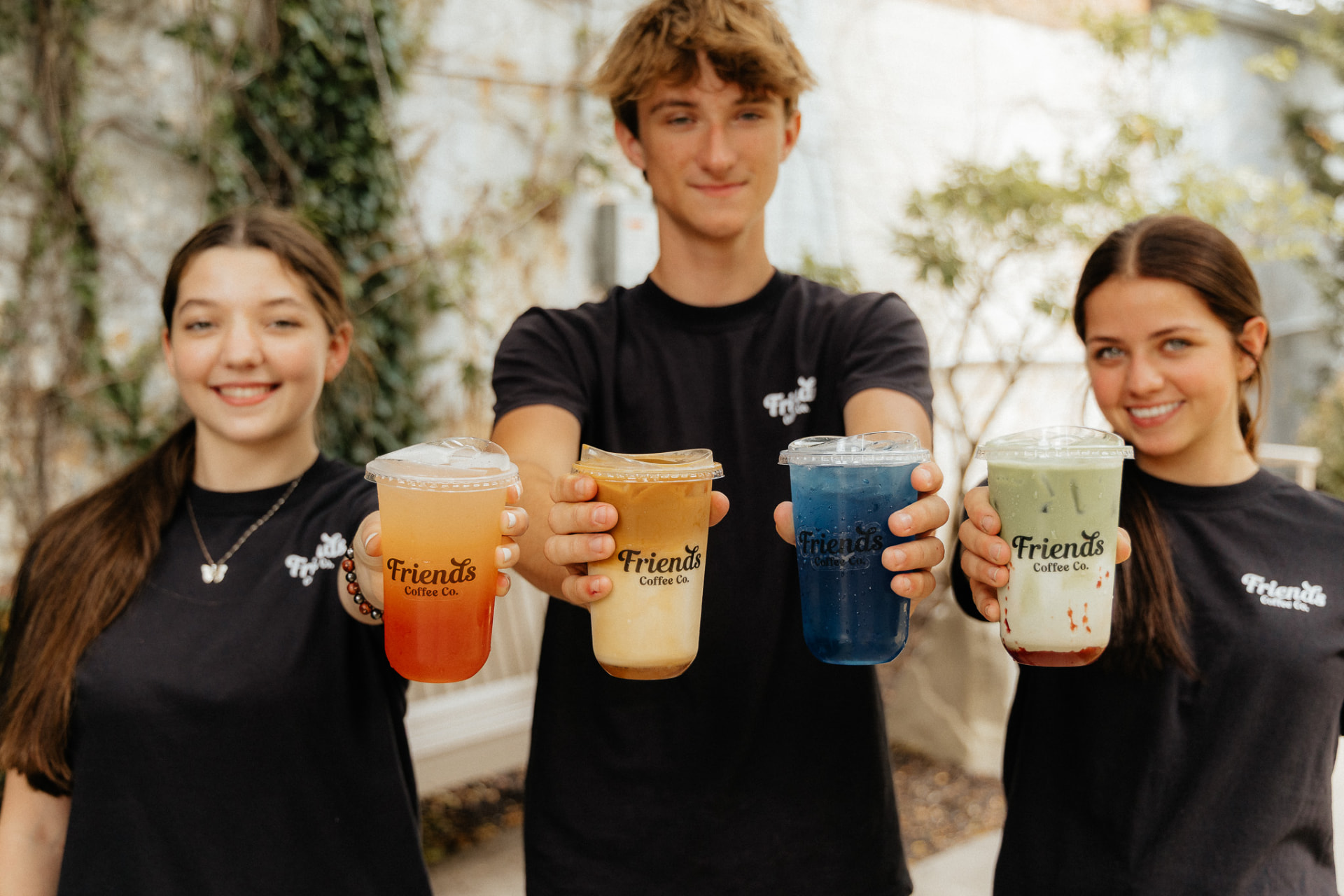 The Friends team holding four specialty drinks